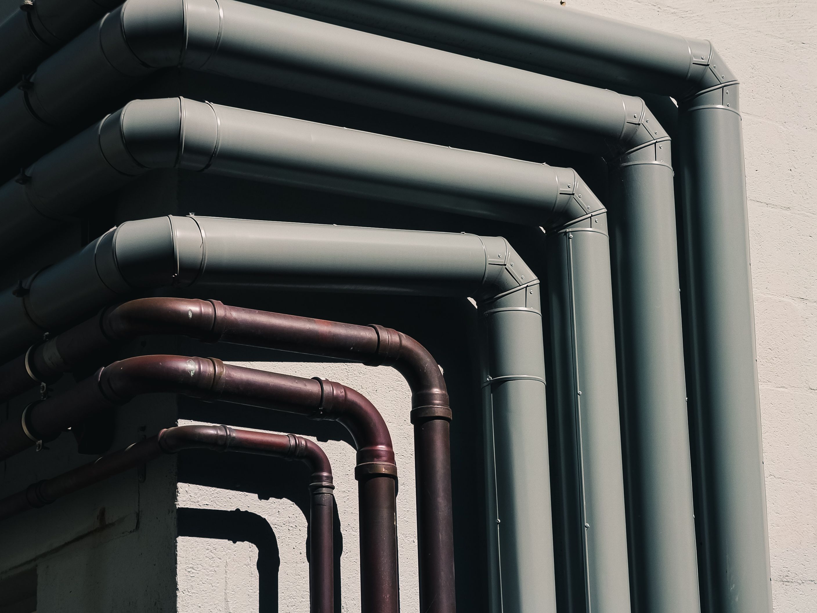 HVAC ductwork and copper plumbing lines running together on a building exterior